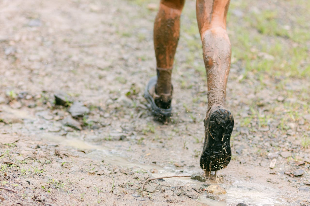 home-hero Close-up of muddy legs running on a wet trail, capturing the thrill of outdoor adventure.